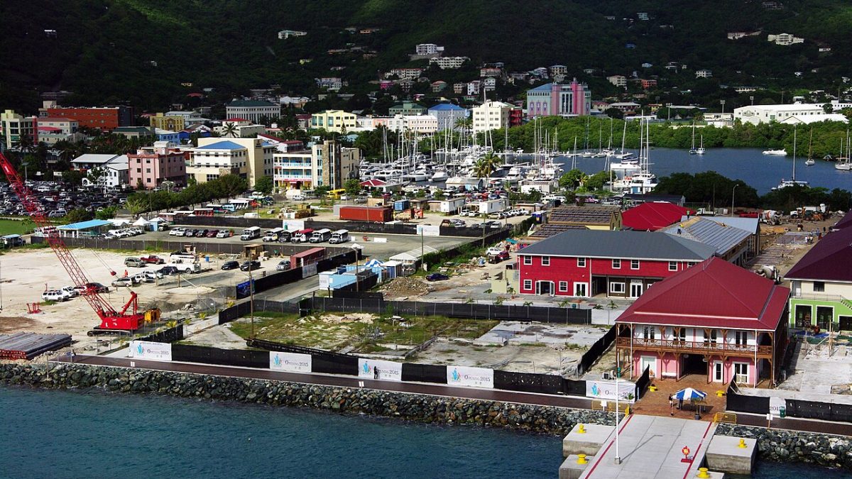 High-angle view of Road Town harbour on Tortola, with colourful waterfront buildings, a marina packed with sailboats, and steep green hills behind the British Virgin Islands capital.